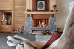 This stunning chalet boasts a rustic-chic living room with a large stone fireplace as the focal point.