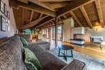 This stunning chalet boasts a spacious open-plan living area with exposed wooden beams, a cozy fireplace, and large windows offering breathtaking mountain views.