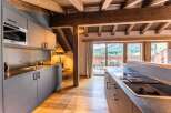 This stunning apartment boasts a modern kitchen with sleek gray cabinetry, integrated appliances, and a breakfast bar, perfect for enjoying meals while taking in the breathtaking mountain views.