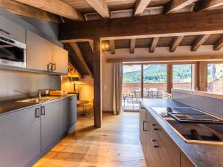 This stunning apartment boasts a modern kitchen with sleek gray cabinetry, integrated appliances, and a breakfast bar, perfect for enjoying meals while taking in the breathtaking mountain views.