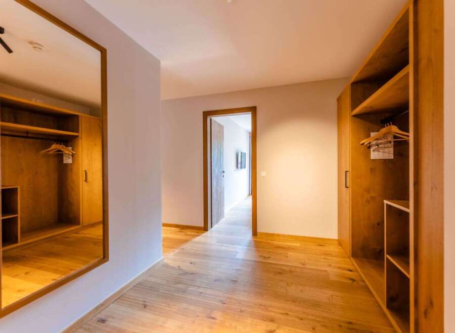 This stunning hallway boasts built-in wooden wardrobes on either side, providing ample storage space.