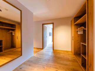 This stunning hallway boasts built-in wooden wardrobes on either side, providing ample storage space.