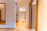 This stunning hallway boasts light oak hardwood flooring, complemented by sleek, modern wooden doors and light walls.