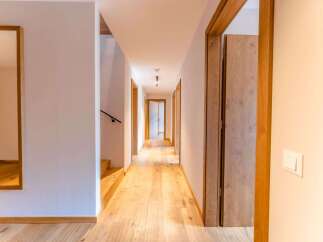 This stunning hallway boasts light oak hardwood flooring, complemented by sleek, modern wooden doors and light walls.