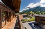 This stunning chalet boasts a spacious wooden deck with mountain views, perfect for relaxing and enjoying the fresh air.