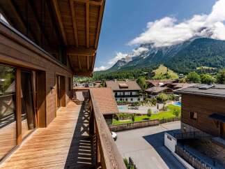 This stunning chalet boasts a spacious wooden deck with mountain views, perfect for relaxing and enjoying the fresh air.