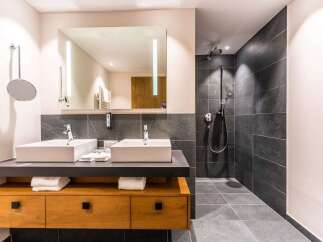 This luxurious bathroom boasts a double vanity with sleek, modern sinks and ample storage.