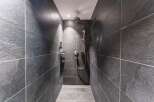 This modern shower features sleek, dark gray slate tiles creating a sophisticated and minimalist aesthetic.