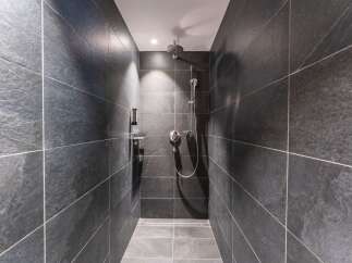 This modern shower features sleek, dark gray slate tiles creating a sophisticated and minimalist aesthetic.