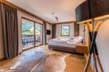 This luxurious bedroom boasts stunning mountain views from its private balcony, accessible through large sliding glass doors.