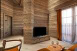 This stunning chalet boasts a cozy living area with a rustic wooden interior, featuring a large flat-screen TV and comfortable seating.