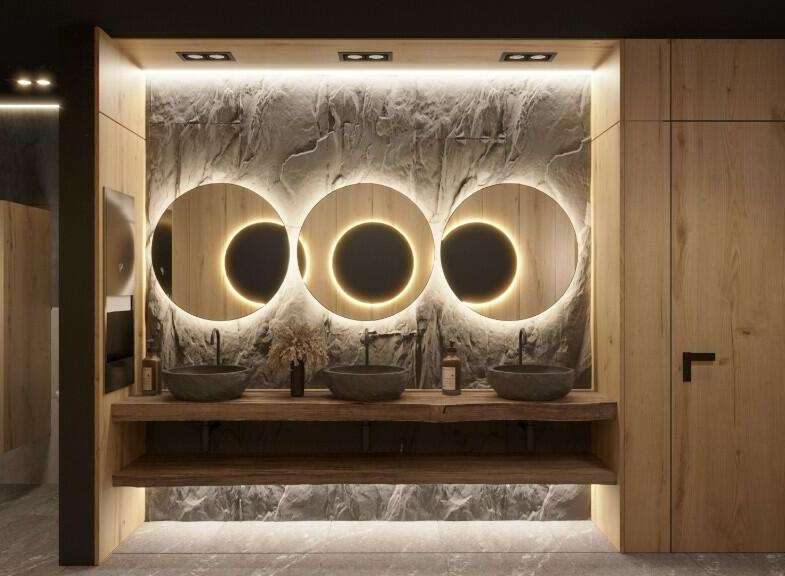 This stunning bathroom boasts a luxurious design with three circular mirrors illuminated by warm lighting, creating a spa-like atmosphere.