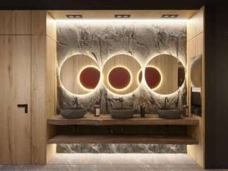 This modern bathroom boasts a stunning stone feature wall, illuminated by recessed lighting, and accented with three circular mirrors with warm LED lighting.