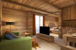 This stunning wooden apartment boasts a cozy living area with a plush green sofa, a large flat-screen TV, and a rustic wooden coffee table.