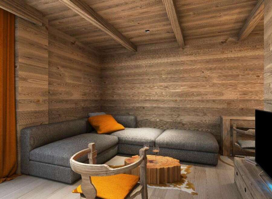 Cozy mountain chalet living room with wood-paneled walls and ceiling, featuring a comfortable gray sectional sofa and a rustic wooden coffee table.
