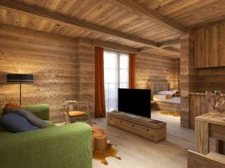 This stunning wooden apartment boasts a cozy living area with a plush green sofa, a large flat-screen TV, and a rustic wooden coffee table.