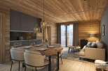This stunning apartment boasts a modern kitchen with dark gray cabinets and wooden accents, seamlessly flowing into a cozy living area with a light beige sofa and wooden flooring.