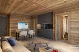 This stunning hotel room boasts a cozy and modern design, featuring a spacious living area with a comfortable sofa and a dining table for four.