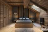 This stunning hotel room boasts a cozy, rustic-chic design with exposed wooden beams, a wood-paneled wall, and a platform bed.