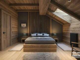 This stunning hotel room boasts a cozy, rustic-chic design with exposed wooden beams, a wood-paneled wall, and a platform bed.