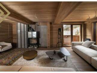 This stunning chalet boasts a spacious living area with floor-to-ceiling windows offering breathtaking mountain views.