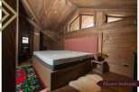 This master bedroom boasts a cozy and rustic atmosphere with wood paneling, a comfortable bed, and a unique rug.