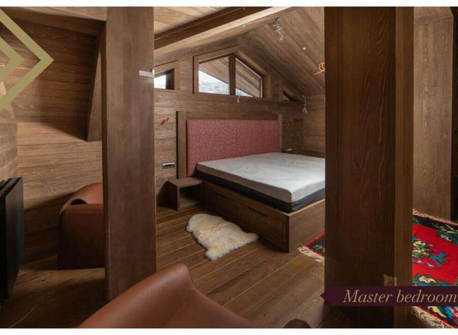 This master bedroom boasts a cozy and luxurious design with a plush bed, wooden floors, and a stunning wooden wall.