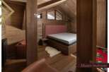 This master bedroom boasts a cozy and luxurious design with a plush bed, wooden floors, and a stunning wooden wall.
