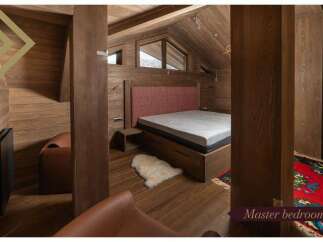This master bedroom boasts a cozy and luxurious design with a plush bed, wooden floors, and a stunning wooden wall.