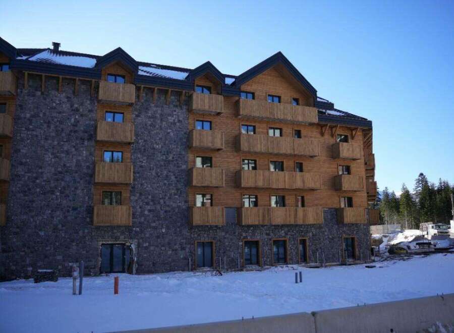 This stunning mountain lodge boasts a unique blend of rustic stone and modern wood, creating a cozy yet sophisticated atmosphere.