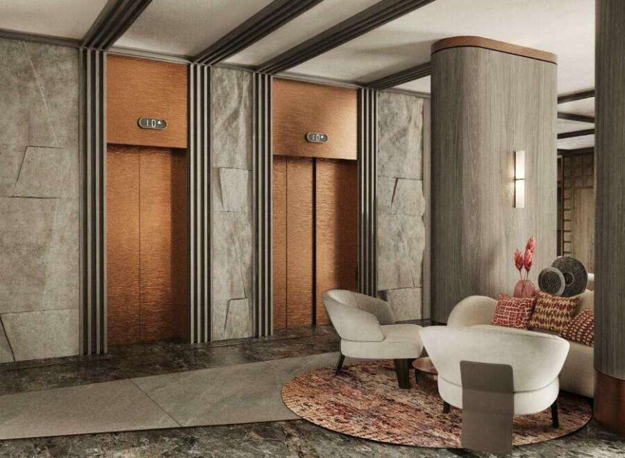 This luxurious lobby boasts two elegant copper elevators framed by textured gray stone walls and sleek dark accents.