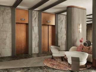 This luxurious lobby boasts two elegant copper elevators framed by textured gray stone walls and sleek dark accents.