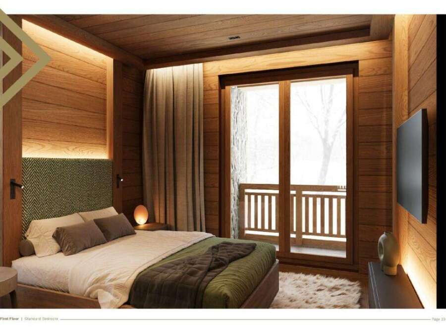 This stunning bedroom boasts a cozy and luxurious design, featuring a plush bed with a green quilted throw, complemented by wooden walls and floors.