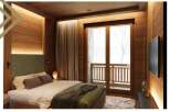 This stunning bedroom boasts a cozy and luxurious design, featuring a plush bed with a green quilted throw, complemented by wooden walls and floors.