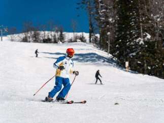 A skier glides down a snowy slope on a sunny day, enjoying the winter wonderland.