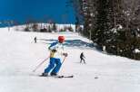 A skier glides down a snowy slope on a sunny day, enjoying the winter wonderland.