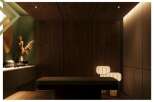 This serene massage room boasts a minimalist design with dark wood paneling, soft lighting, and calming decor.