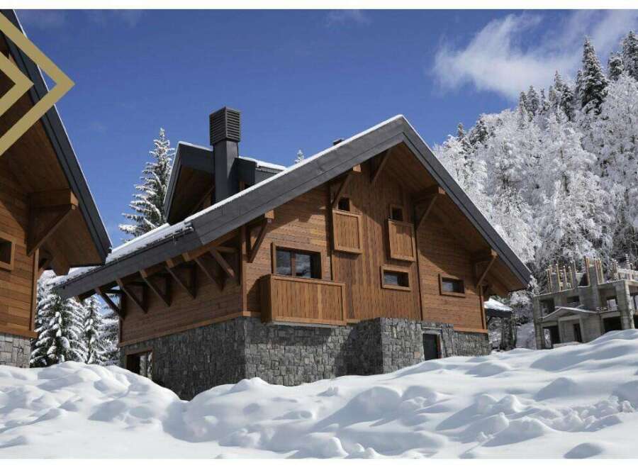 This stunning chalet boasts a beautiful wooden exterior, complemented by a stone base, offering a cozy and luxurious feel.