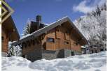 This stunning chalet boasts a beautiful wooden exterior, complemented by a stone base, offering a cozy and luxurious feel.
