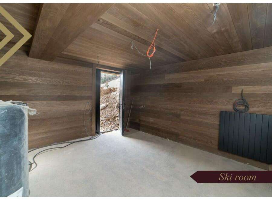 This stunning ski room boasts a modern design with sleek dark wood paneling on the walls and ceiling, creating a warm and inviting atmosphere.