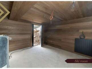 This stunning ski room boasts a modern design with sleek dark wood paneling on the walls and ceiling, creating a warm and inviting atmosphere.