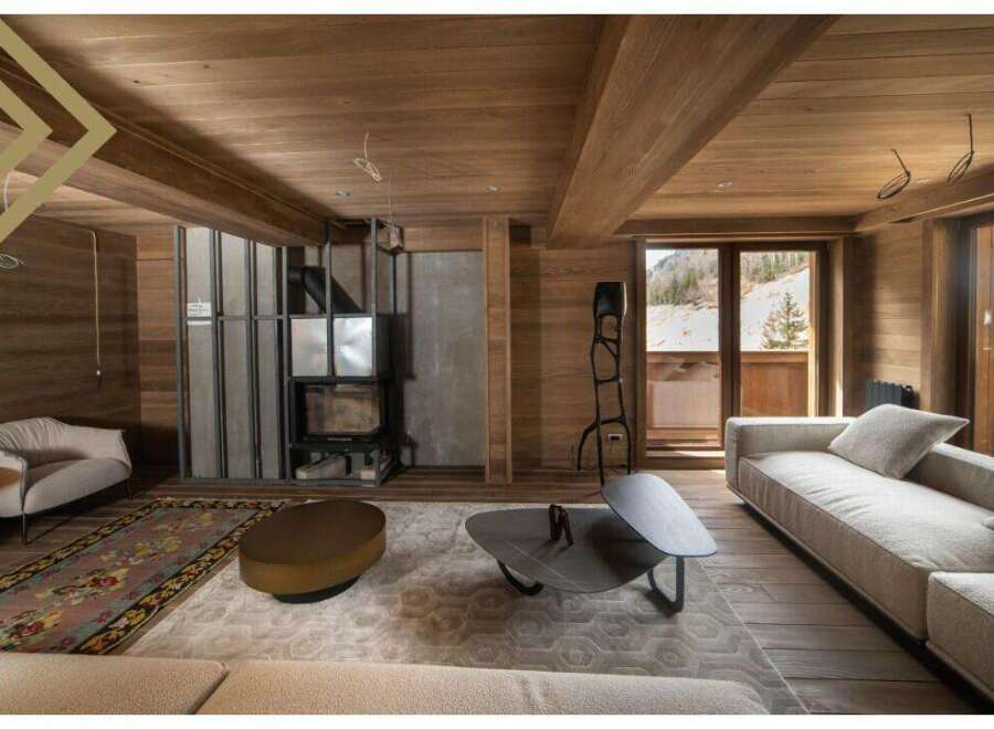 This stunning chalet boasts a spacious living area with floor-to-ceiling windows offering breathtaking mountain views.
