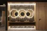 This stunning bathroom boasts a luxurious design with three circular mirrors illuminated by warm lighting, creating a spa-like atmosphere.