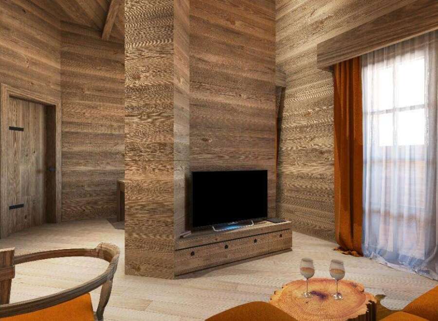 This stunning chalet boasts a cozy living area with a rustic wooden interior, featuring a large flat-screen TV and comfortable seating.