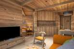 This stunning wooden chalet boasts a cozy living area with a comfortable sofa, a rustic wooden chair, and a modern flat-screen TV.