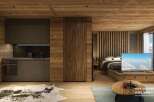 This stunning hotel room boasts a modern kitchen with dark gray cabinetry and wooden accents, seamlessly integrated into a cozy living space.