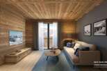 This stunning hotel room boasts a cozy living area with a comfortable sofa, a large TV, and a wooden coffee table.
