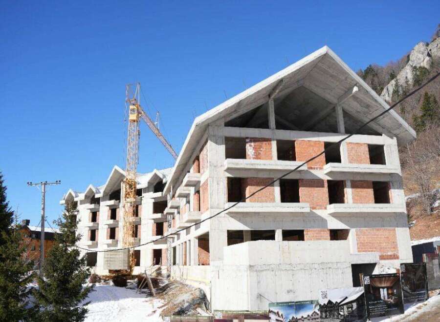 This stunning property is currently under construction, boasting a modern design with a sleek concrete exterior and large windows.