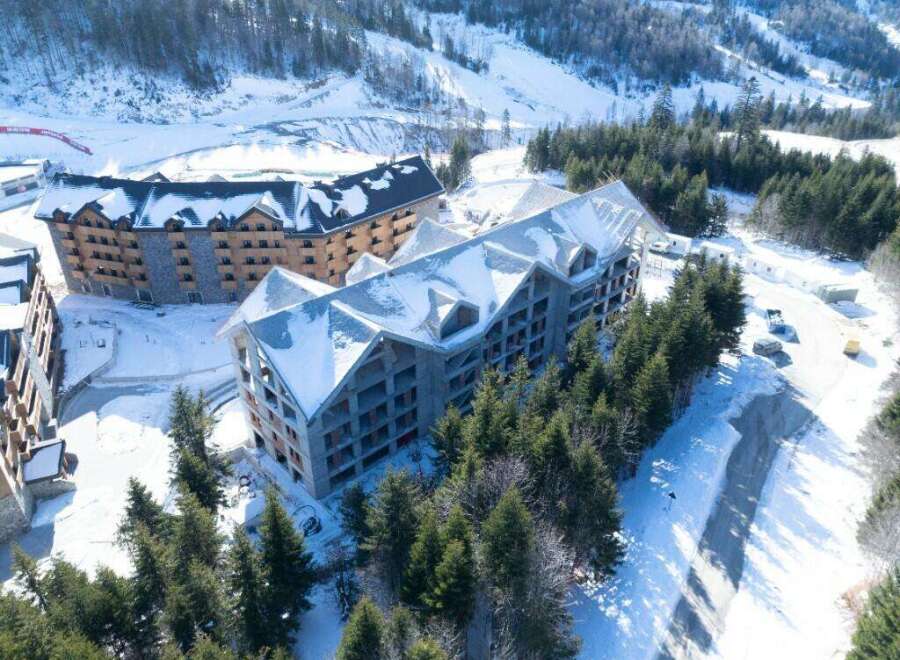 Luxury ski resort nestled in a snowy mountainside, featuring stunning aerial views of modern architectural design.