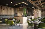 This modern restaurant boasts a sleek design with dark wood accents, green velvet chairs, and unique wall art.